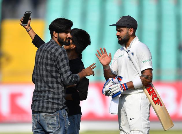 Indian cricket captain Virat Kohli talks with pitch inavders trying to take a selfie with him during the first day's play of the first Test cricket match between India and West Indies.(AFP)