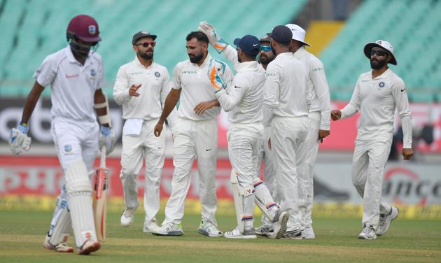 West Indies batsman Kraigg Brathwaite (L) walks back as teammates congratulate India's Mohammed Shami for his wicket during the second day's play of the first Test cricket match between India and West Indies at the Saurashtra Cricket Association stadium in Rajkot. (AFP)