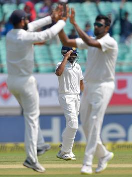 India's Cheteshwar Pujara (L) and Ravichandran Ashwin (R) celebrate as India's Prithvi Shaw (background C) salutes after taking a catch to dismiss West Indies batsman Keith Brathwaite during the third day's play of the first Test cricket match between India and West Indies at the Saurashtra Cricket Association stadium in Rajkot . (AFP)