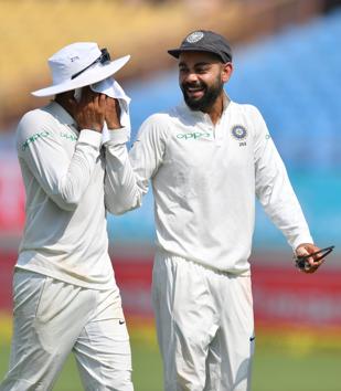 Indian captain Virat Kohli (R) shares a light moment with teammate Ravindra Jadeja during the third day's play of the first Test cricket match between India and West Indies at the Saurashtra Cricket Association Stadium in Rajkot. (AFP)