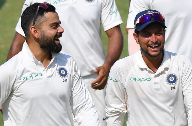 Indian captain Virat Kohli along with teammate Kuldeep Yadav laugh as they walk back after winning the first Test cricket match between India and West Indies at the Saurashtra Cricket Association Stadium in Rajkot. (AFP)