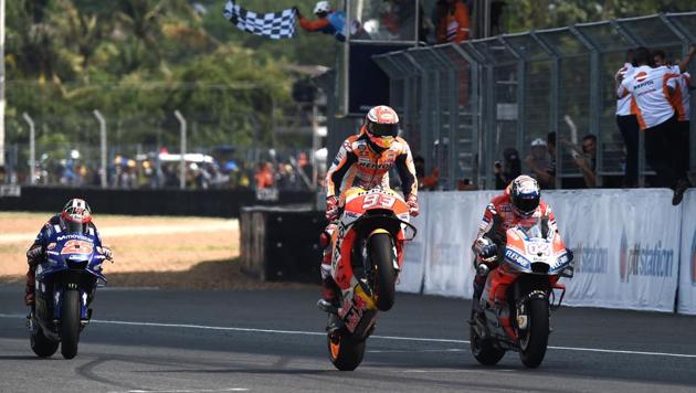 Repsol Honda Team's Spanish rider Marc Marquez (C) celebrates on the track flanked by Ducati Team's Italian rider Andrea Dovizioso (R) and Third placed Movistar Yamaha MotoGP's(AFP)