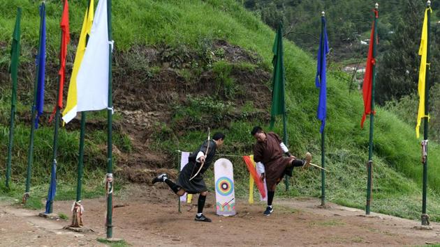 Archers performs a leg-kicking dance after hitting the target. A war cry rings out each time the target is hit. Players in traditional “gho” dresses dance and sing folk numbers -- different ones for winning and losing. The crucial drink breaks see archers gulp down locally brewed whisky before locking horns again on the field where colourful flags flutter in the breeze. (Arun Sankar / AFP) 