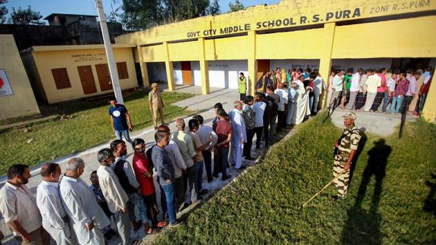 Security personnel stands guard as people wait in queues to cast their votes for municipal elections in Ranbir Singh Pura near Jammu on Monday. (PTI Photo) Security personnel stands guard as people wait in queues to cast their votes for municipal elections in Ranbir Singh Pura near Jammu on Monday. (PTI Photo)