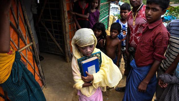 Saleema steps carefully through the crowded alleyways in Kutupalong with her blue-bound Quran held tight to her chest, removes her shoes and enters the dimly-lit classroom. Since formal schooling -- which suggests a permanent presence -- is not allowed in the camps, for many children the madrassas are the only places to learn. (Chandan Khanna / AFP) Saleema steps carefully through the crowded alleyways in Kutupalong with her blue-bound Quran held tight to her chest, removes her shoes and enters the dimly-lit classroom. Since formal schooling -- which suggests a permanent presence -- is not allowed in the camps, for many children the madrassas are the only places to learn. (Chandan Khanna / AFP)