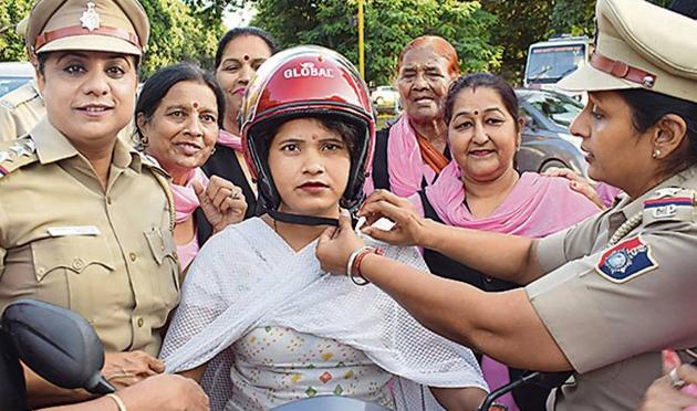 Cops giving a helmet to a woman rider as part of an awareness drive in Chandigarh on Thursday. (SS Chopra/Ht) Cops giving a helmet to a woman rider as part of an awareness drive in Chandigarh on Thursday. (SS Chopra/Ht)