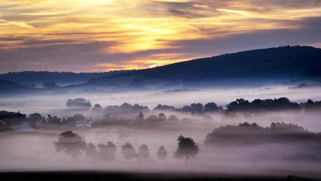 Fog sits on the fields of a village near Kassel, central Germany, just before sunrise. (Michael Probst / AP)