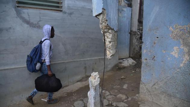 A girl walks next to a house that suffered some damage after an earthquake hit the city of Port-de-Paix, Haiti. (Hector Retamal / AFP)