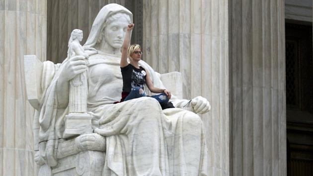 Demonstrator Jessica Campbell-Swanson of Denver, Colorado, sits on the lap of the ‘Contemplation of Justice’ statue as protestors take the steps of the US Supreme Court against the appointment of Supreme Court nominee Brett Kavanaugh in Washington DC. (Jose Luis Magana / AFP)