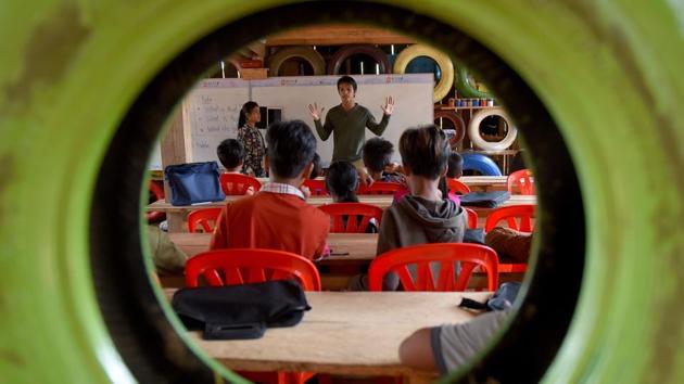 Ouk Vandey, known as the Rubbish Man (C) teaches students at the Coconut School at Kirirom national park in Kampong Speu province, Cambodia. Sitting in a building made from used tyres, plastic bottles and old sneakers, Roeun Bunthon jots down notes during an English lesson at the “Rubbish School” where tuition is paid for with trash instead of cash. (Tang Chhin Sothy / AFP)