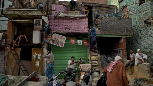Migrant workers from eastern India prepare themselves for the day outside their cramped accommodation in the old quarters of Delhi. (R S Iyer / AP)