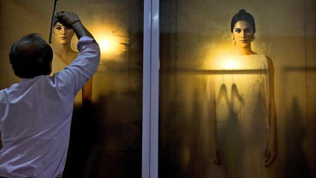 A worker pastes a photograph of a model at the exhibition centre of various designers at the start of the Lotus Makeup India Fashion Week in New Delhi, India. (Manish Swarup / AP)