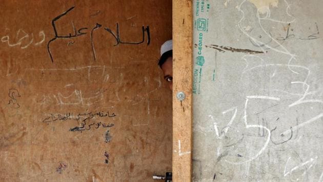 A boy from the Rohingya community peeps out from the door of a madrasa, or a religious school, at a camp on the outskirts of Jammu, Jammu and Kashmir. (Mukesh Gupta / REUTERS)