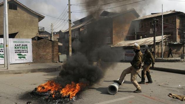 Policemen try to douse a fire during protests following an encounter in Srinagar on Wednesday.(Waseem Andrabi/ HT)