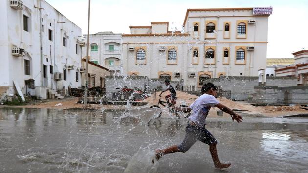 Children from a local neighbourhood play in a roadside puddle accumulated from rain brought by Cyclone Luban in Salalah, Oman. (Stringer / REUTERS)