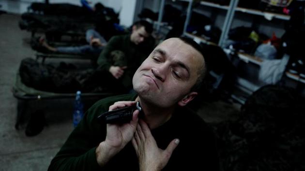 Marcin Wierzbicki, 44, a manager in an energy company, shaves during his 16-day basic training. “I am a pragmatist and I believe that we will not take part in battles,” he said. “We will take care of things that are necessary for people, such as guarding key objects, controlling road points, defending population of course, and minimising the impact of an attack on the community.” (Kacper Pempel / REUTERS)