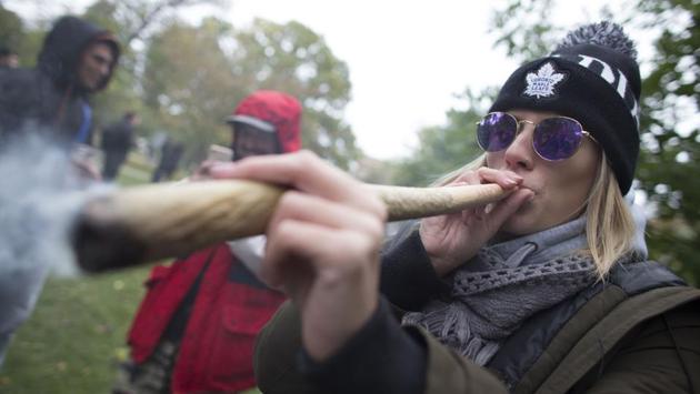 A woman smokes a huge marijuana cigarette during a legalization party at Trinity Bellwoods Park in Toronto, Ontario. (Geoff Robins / AFP)