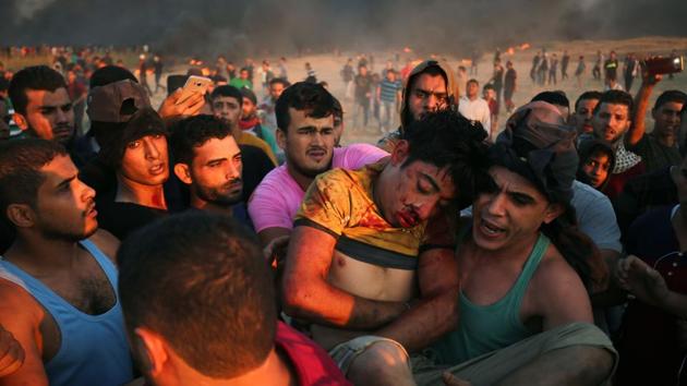 Palestinian protesters carry a youth injured by Israeli forces at the Israel-Gaza border. Five Palestinians were killed in new clashes with Israeli forces along the Gaza border on October 12, the health ministry in the Hamas-run enclave said. (Said Khatib / AFP)