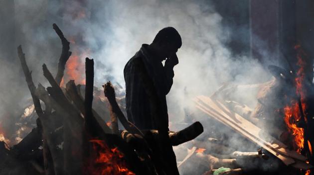 A man cries as he stands next to the burning pyre of a family member who was crushed to death on the rail tracks on Friday, at a cremation ground in Amritsar, on October 20, 2018.(Reuters)