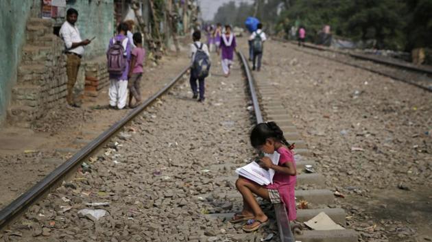 A young girl browses through books while sitting on a railway track in New Delhi. (Altaf Qadri / AP) A young girl browses through books while sitting on a railway track in New Delhi. (Altaf Qadri / AP)