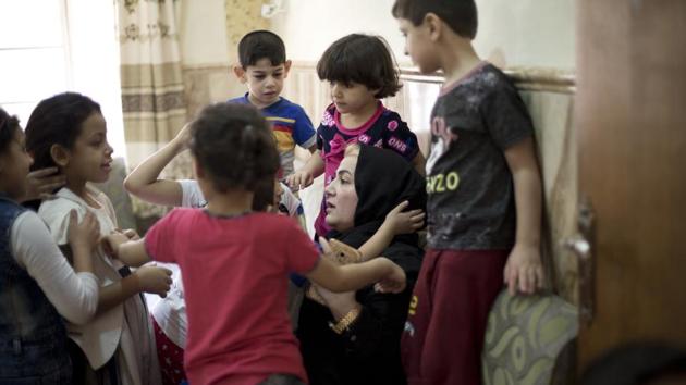 Children gather around Sukaina Mohammed Ali, a top official of the local Mosul government, at an orphanage in Mosul, Iraq. The older of the two orphanages was founded in 2017 by Ali, who says she begged and prayed for donations to feed and clothe the children before government funds were made available. (Maya Alleruzzo / AP) 
