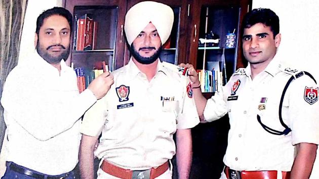 Mohali MLA Balbir Singh Sidhu’s brother Amarjit Singh Jiti (left) pinning stars on ASI Harjinder Singh’s uniform.(HT Photo)