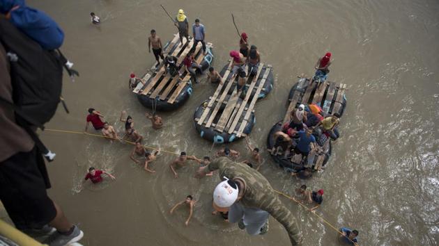 Migrants tired of waiting to cross into Mexico, jumped from a border bridge into the Suchiate River, in Tecun Uman. Some of the migrants organized a rope brigade to ford its muddy waters. The first waves began arriving in Huixtla after an exhausting eight-hour trek and quickly staked out grassy spots in the town square to bed down overnight. (Oliver de Roos / AP) Migrants tired of waiting to cross into Mexico, jumped from a border bridge into the Suchiate River, in Tecun Uman. Some of the migrants organized a rope brigade to ford its muddy waters. The first waves began arriving in Huixtla after an exhausting eight-hour trek and quickly staked out grassy spots in the town square to bed down overnight. (Oliver de Roos / AP)
