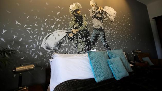Graffiti work by Banksy showing an Israeli soldier and masked Palestinian youth having a pillow fight. Three Banksy prints went under the hammer in Paris on Wednesday, a first auction of his works since a print that sold in London earlier this month for $1.37 million was half shredded in a stunt after the hammer fell. (Mussa Qawasma / REUTERS)