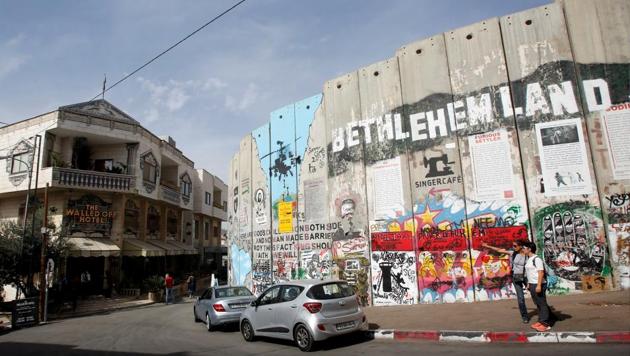 British street artist Banksy's Walled Off Hotel (L) opposite a section of the Israeli barrier in Bethlehem, occupied West Bank. The hotel is situated a few metres from Israel’s separation barrier and Banksy has described the guesthouse as having the worst view of any hotel in the world, with windows overlooking the controversial wall that separates the West Bank from Israel. (Mussa Qawasma / REUTERS)