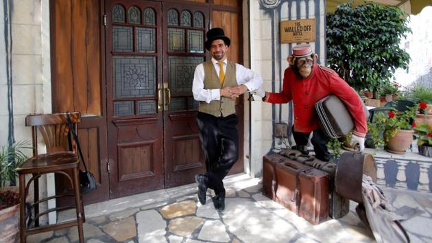 A staff looks on as a statue of a clumsy chimpanzee bell-boy is seen at the entrance of the Walled Off Hotel. Guests at the hotel, which opened last year, leave admiring the elusive artist’s work, whose wall paintings and other works adorn this statement establishment. (Mussa Qawasma / REUTERS)