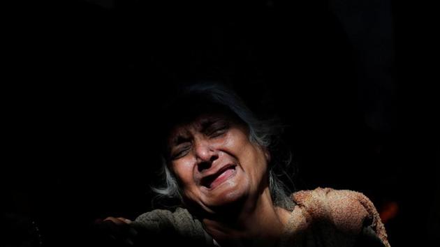 A woman cries next to the burning pyre of a family member who died after a commuter train travelling at high speed ran through a crowd of people on the rail tracks on Friday, at a cremation ground in Amritsar, Punjab. (Adnan Abidi / REUTERS)