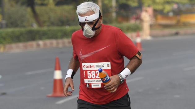 A runner wears a mask during the Airtel Delhi Half Marathon at Rajpath in New Delhi. On Thursday, Delhi also witnessed its coldest day of the season so far, when the minimum temperature dropped to 15 degrees Celsius, two degrees below normal. (Burhaan Kinu / HT Photo) 