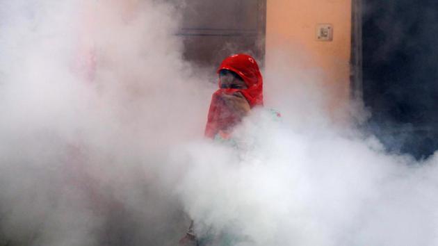 A woman covers her face while engulfed by fumes during fumigation work carried out by a municipal worker at a residential locality in New Delhi. (Anushree Fadnavis / REUTERS)
