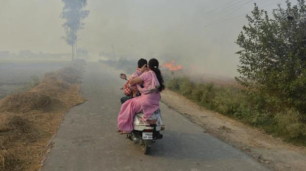 A couple on a scooter ride through smoke caused by farmers burning crop stubble on the outskirts of Amritsar, Punjab. (Prabhjot Gill / AP)