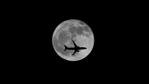 A passenger plane passes the moon as it comes into land at the international airport in Chennai.(REUTERS)