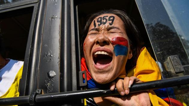 An exiled Tibetan youth shout slogans from a police bus as she protests against a visit of Chinese ministers including the minister of public security Zhao Kezhi and other high-level ministers to India in New Delhi. (Chandan Khanna / AFP)