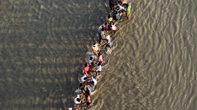 Indian labourers pull a pontoon buoy with a rope in the river Ganges as they build a floating pontoon bridge over the river Ganga for the upcoming Kumbh Mela festival. (Sanjay Kanojia / AFP)