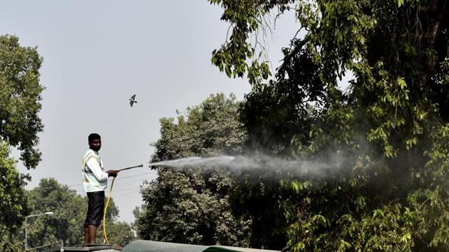NDMC worker spray water to clean dust gathered on trees at Mansingh Road as pollution mounts in the national capital on October 17, 2018. The Supreme Court on Tuesday also set a two-hour window for the use of low-emission firecrackers on Diwali night but didn’t impose any ban on the sale of firecrackers in the National Capital Region. (Vipin Kumar / HT Photo) 