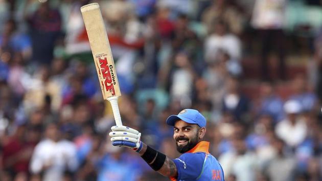 Indian cricket captain Virat Kohli raises his bat to celebrate scoring 10,000 runs in one-day internationals during the second ODI match between India and West Indies in Visakhapatnam, Andhra Pradesh. (Aijaz Rahi / AP)