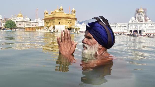 A devotee takes bath in the holy sarovar (water tank) and pays obeisance at the Golden Temple on the occasion of birth anniversary of Guru Ram Das in Amritsar on Friday (Sameer Sehgal/HT)