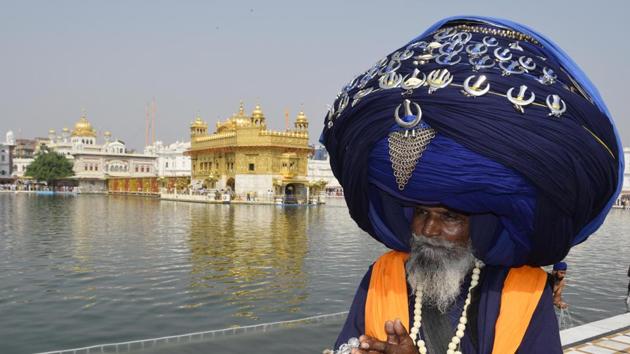 Nihang Jagir Singh wearing a 313 metre turban pays obeisance at the Golden Temple on Friday. (Sameer Sehgal/HT)
