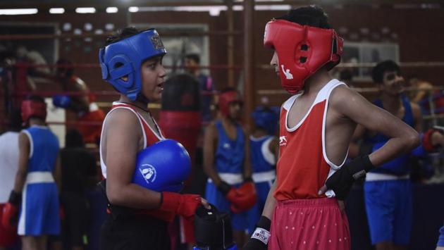 Kitted up for training, children talk during a break. There are many villages in Najafgarh that now have their own boxing academies. Delhi Rural Boxing Academy in Baprola, the native village of Olympic silver-winning wrestler Sushil Kumar is one example. Anil Solanki, its founder said that many children from economically weaker families are getting into boxing, which they feel will help change their fortunes. (Vipin Kumar / HT Photo) 