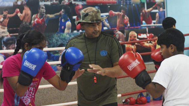 Boxing coach Anil Fauji trains students. Najafgarh Boxing Academy, which started three years ago, has 125 students and claims 40 national level players as products. The academy’s brick-red walls have black and white posters of American boxers, such as Floyd Mayweather, Mike Tyson, Muhammad Ali and Indian boxing champions such Mary Kom, Akhil Kumar, Vijender Singh and Vikas Krishnan, among others. (Vipin Kumar / HT Photo) 