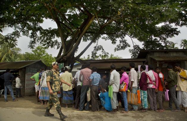 A security personnel walks past as people whose names were left out in the National Register of Citizens (NRC) draft stand to collect forms to file appeals near a NRC centre on the outskirts of Guwahati in Assam.(AP FILE PHOTO)