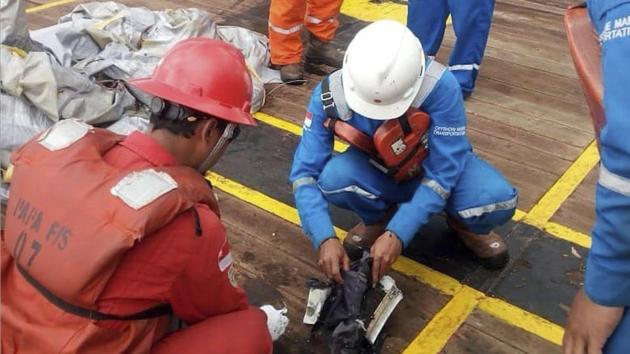 Rescuers inspect debris believed to be from the crashed Lion Air passenger jet. Indonesia’s disaster agency posted photos online of a crushed smartphone, books, bags and parts of the aircraft fuselage that had been collected by search and rescue vessels that have converged on the area. (BNPB via AP)