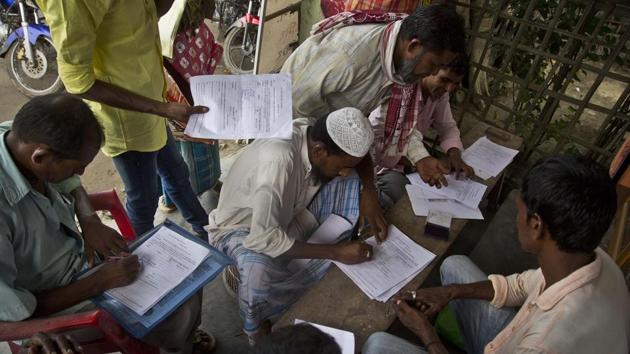 People whose names were left out in the National Register of Citizens (NRC) draft fill their forms to file appeals near a NRC center on the outskirts of Guwahati.(AP File Photo)