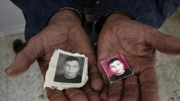 Photos of Majdi Al Barhoumi, who went missing in 2011, held out by his father in Ras Jabal. Migrants who go missing are a daily reproach to political failure, so there is rarely an official count of the departed, the dead or the disappeared. (Nariman El-Mofty / AP) Photos of Majdi Al Barhoumi, who went missing in 2011, held out by his father in Ras Jabal. Migrants who go missing are a daily reproach to political failure, so there is rarely an official count of the departed, the dead or the disappeared. (Nariman El-Mofty / AP)