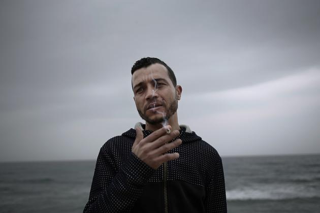 In this April 14, 2018 photo, 32-year old Ahmed Ayouby, who wants to leave Tunisia, smokes a cigarette at the beach where migrants leave for Italy, in the town of Ras Jabal, Bizerte, Tunisia. From the closest points to Europe in Tunisia, Ras Jebel in the north and the Kerkennah Islands in the east, it's a half-day sail if all goes well. (AP Photo/Nariman El-Mofty) (AP) In this April 14, 2018 photo, 32-year old Ahmed Ayouby, who wants to leave Tunisia, smokes a cigarette at the beach where migrants leave for Italy, in the town of Ras Jabal, Bizerte, Tunisia. From the closest points to Europe in Tunisia, Ras Jebel in the north and the Kerkennah Islands in the east, it's a half-day sail if all goes well. (AP Photo/Nariman El-Mofty) (AP)