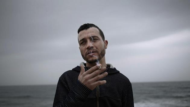 32-year old Ahmed Ayouby, who wants to leave Tunisia, smokes a cigarette at the beach where migrants leave for Italy. The Mediterranean has been robbing Tunisia of its young, who abandon their homeland in hopes of a better life in Europe. At the closest points, Ras Jebel in the north and the Kerkennah Islands in the east, it’s a half-day sail if all goes well. (Nariman El-Mofty / AP) 32-year old Ahmed Ayouby, who wants to leave Tunisia, smokes a cigarette at the beach where migrants leave for Italy. The Mediterranean has been robbing Tunisia of its young, who abandon their homeland in hopes of a better life in Europe. At the closest points, Ras Jebel in the north and the Kerkennah Islands in the east, it’s a half-day sail if all goes well. (Nariman El-Mofty / AP)