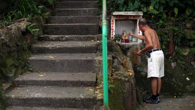 Tim Man Kwok, 72, lights incense next to a statue of the Chinese God of Land at the Sai Wan Swimming Shed. The location is just a stone’s throw from the heart of the financial centre against a busy backdrop of container ships, ferries and fishing boats. (REUTERS / Hannah McKay) Tim Man Kwok, 72, lights incense next to a statue of the Chinese God of Land at the Sai Wan Swimming Shed. The location is just a stone’s throw from the heart of the financial centre against a busy backdrop of container ships, ferries and fishing boats. (REUTERS / Hannah McKay)